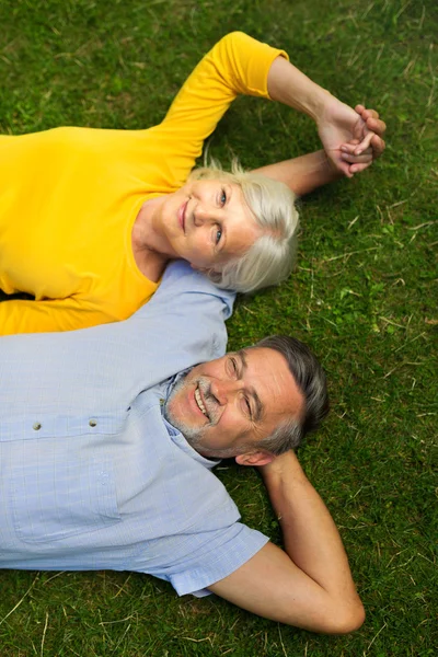 Seniorenpaar liegt im Gras — Stockfoto