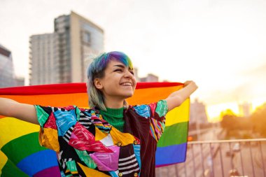 Portrait of happy non-binary person waving rainbow flag clipart