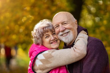 Mutlu son sınıf çifti, sonbaharda güzel şehir parkında birlikte vakit geçiriyor.