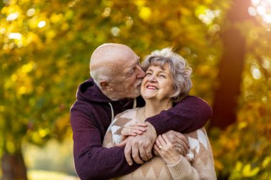 Mutlu son sınıf çifti, sonbaharda güzel şehir parkında birlikte vakit geçiriyor.