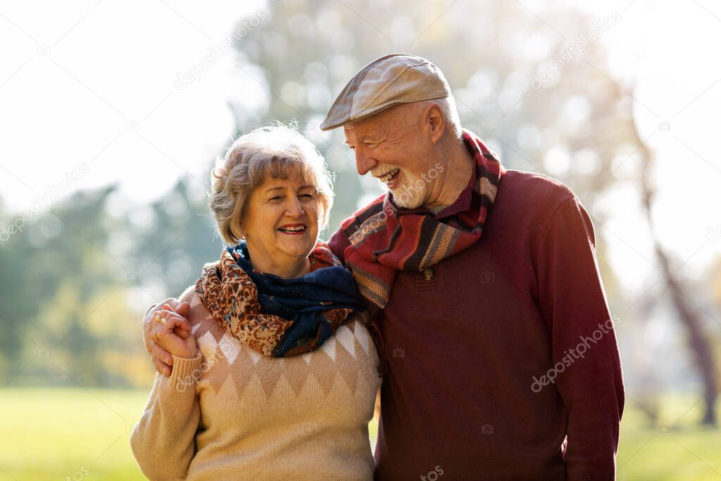 Happy senior couple spending time together in beautiful city park in autumn