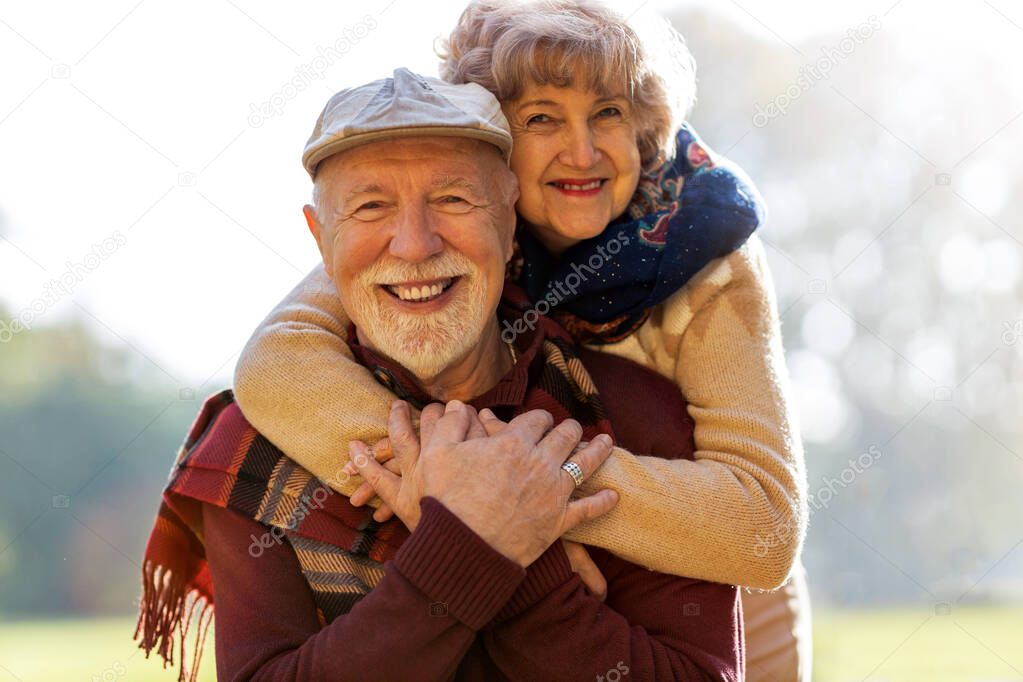 Happy senior couple spending time together in beautiful city park in autumn