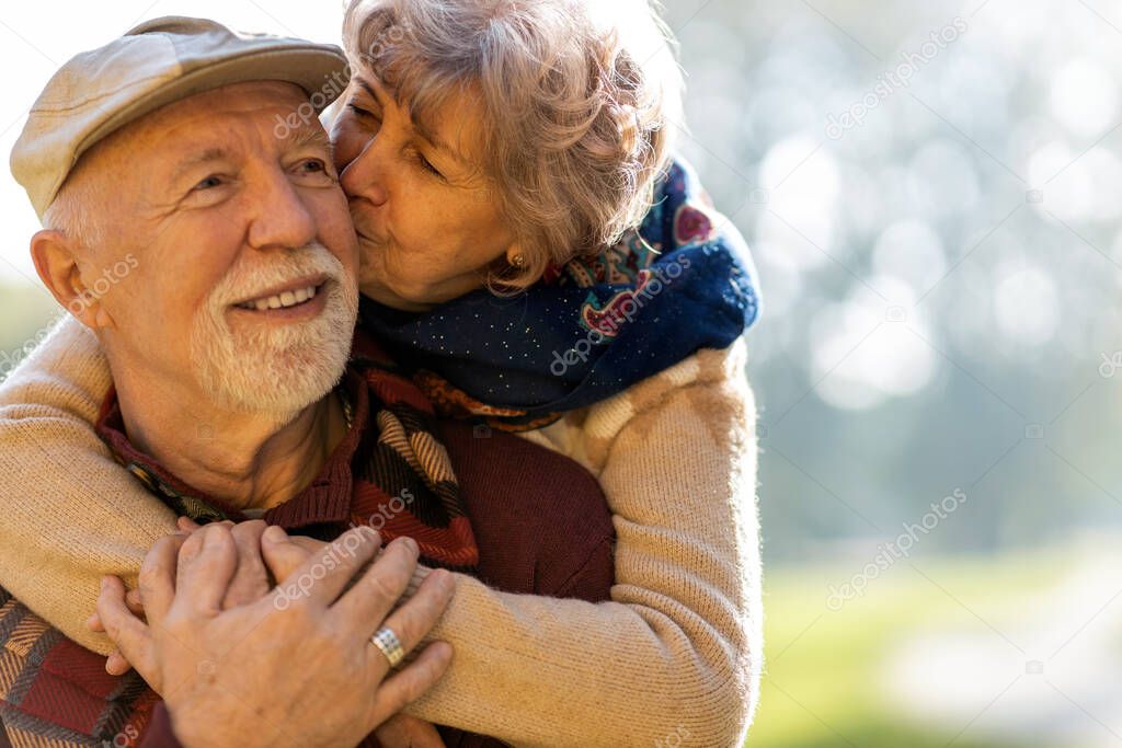 Happy senior couple spending time together in beautiful city park in autumn