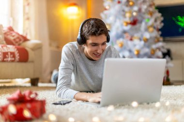 Genç çocuk Noel zamanı evde dizüstü bilgisayar kullanıyor.