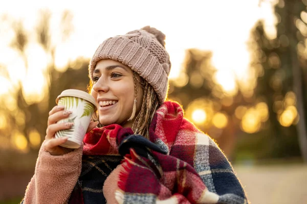 冬の間に屋外で笑顔コーヒーカップを持つ若い女性 — ストック写真