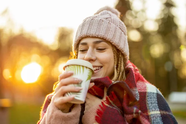 冬の間に屋外で笑顔コーヒーカップを持つ若い女性 — ストック写真