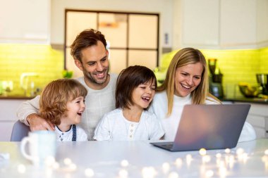 Evde dizüstü bilgisayar kullanan mutlu bir aile.