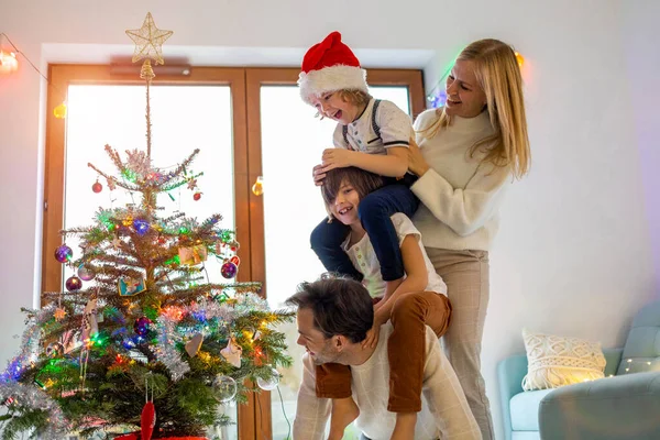 クリスマスツリーを飾る楽しみを持っている若い家族 — ストック写真