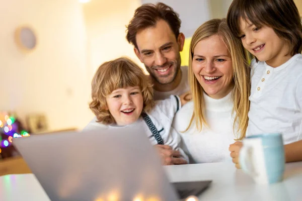 Glad Ung Familj Med Bärbar Dator Hemma Stockbild