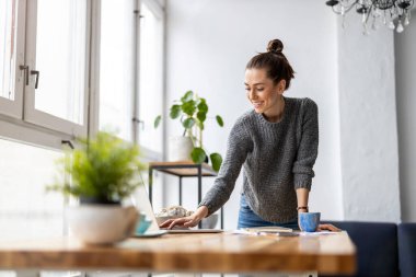 Stüdyosunda dizüstü bilgisayarla çalışan yaratıcı genç bir kadın.