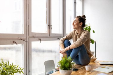Modern bir çatı katında gülümseyen yaratıcı bir kadının portresi.