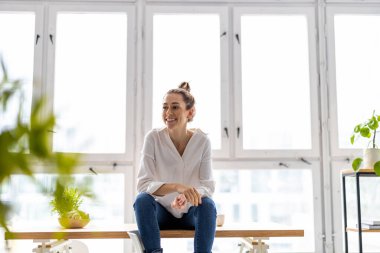 Modern bir çatı katında gülümseyen yaratıcı bir kadının portresi.