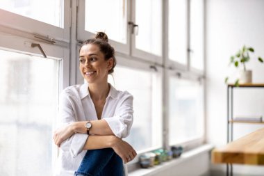 Modern bir çatı katında gülümseyen yaratıcı bir kadının portresi.