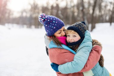 Anne ve oğlu dışarıda karda sarılıyor.