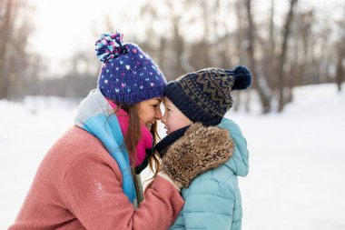 Anne ve oğlu dışarıda karda sarılıyor.