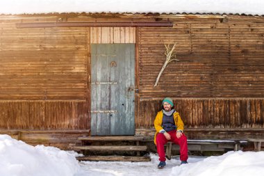 Polonya 'da geleneksel ahşap kulübenin önünde oturan adam.