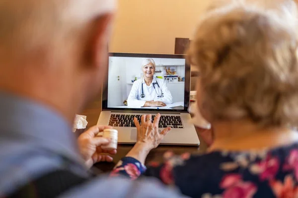 Senior couple consulting with a doctor on laptop at home