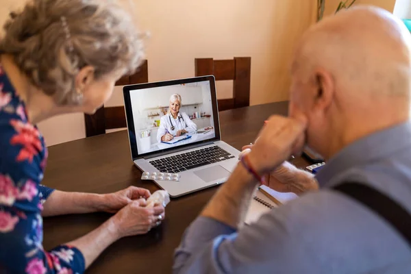 上了年纪的夫妇在家里用笔记本电脑咨询医生 — 图库照片