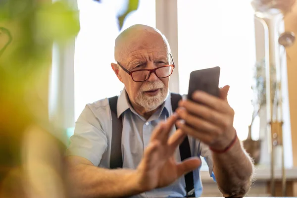 老年人困惑地盯着他的智能手机 — 图库照片
