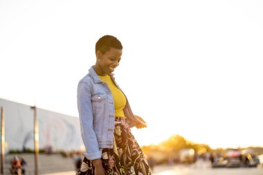 Gülümseyen genç kadın gün batımında dışarıda eğleniyor. 
