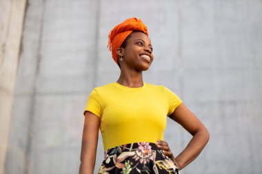 Gri duvarın önünde gülümseyen güzel genç kadın. 