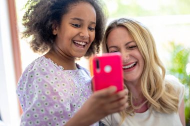 Anne ve küçük kızı evde selfie çekiyorlar.