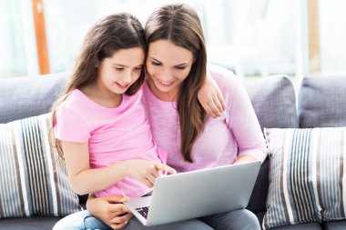 Annesi ve kızı dizüstü bilgisayarlı.