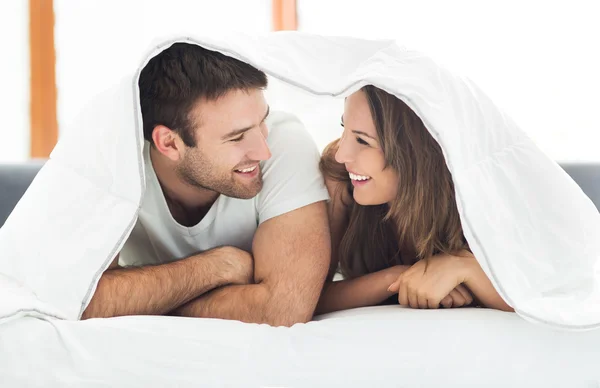 Pareja bajo cama cubre — Foto de Stock