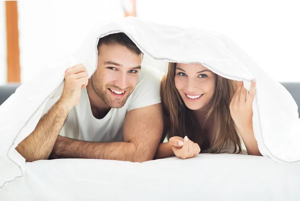 Paar unter Bettdecken — Stockfoto