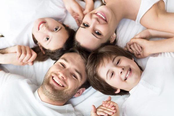 Семья из четырех человек лежит на кровати — стоковое фото