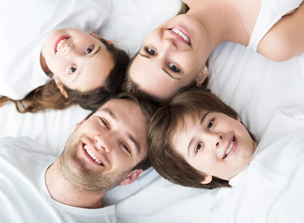 Vierköpfige Familie liegt auf Bett — Stockfoto