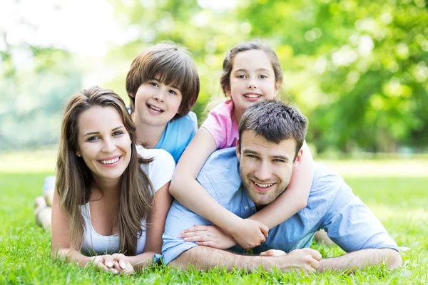 Happy young family lying on grass — Stock Photo, Image