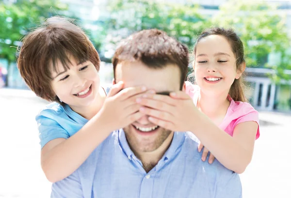 Crianças fechando os olhos do pai e sorrindo — Fotografia de Stock