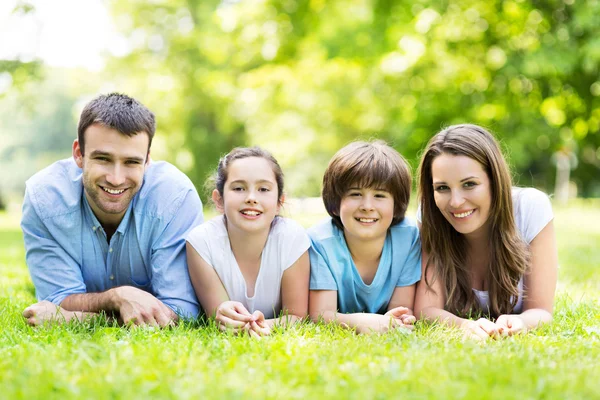 Счастливая молодая семья лежит на траве — стоковое фото