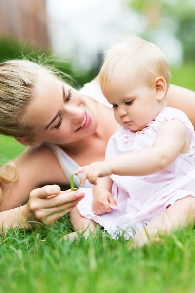 Madre y el bebé juegan en la hierba verde — Foto de Stock