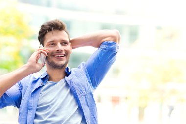 Genç adam dışarıda cep telefonu kullanıyor.