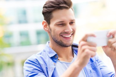 Genç adam dışarıda cep telefonu kullanıyor.