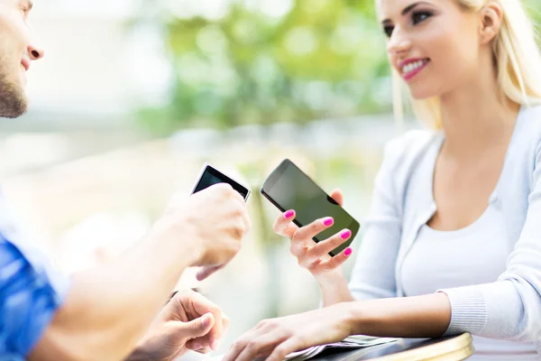 Couple using smartphones to share files — Stock Photo, Image