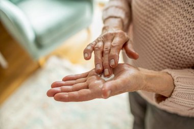 Senior woman applying moisturizer to her hands, close-up