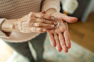 Senior woman applying moisturizer to her hands, close-up
