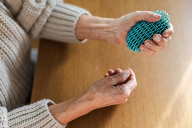 Close-up of elderly persons hands exercising with a therapeutic squeeze toy 