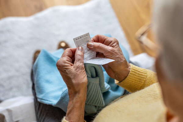 Close up of an elderly woman's hands holding a laundry label