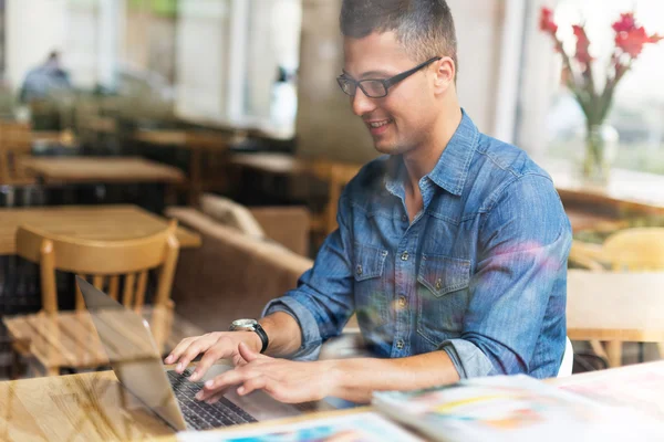 Joven usando el ordenador portátil en la cafetería — Foto de Stock