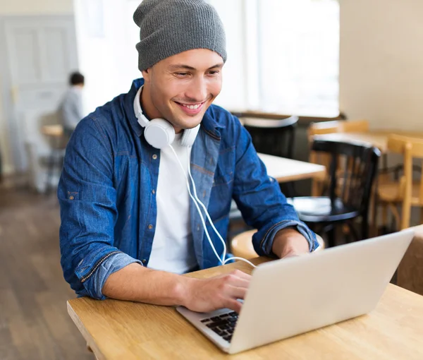 Joven usando el ordenador portátil en la cafetería —  Fotos de Stock