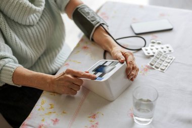 Evde tansiyonunu ölçen yaşlı bir kadın.