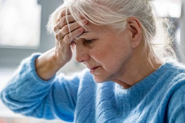 Yaşlı kadın baş ağrısı çekiyor.