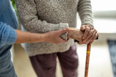 Huzurevinde bakıcısıyla el ele tutuşan yaşlı bir kadın.