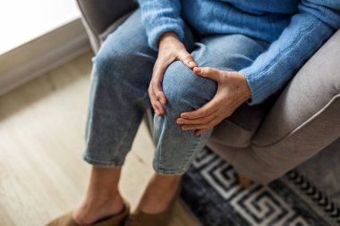 Diz ağrısı çeken yaşlı bir kadın.