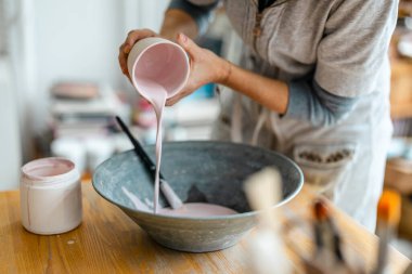 Çömlek atölyesinde boyayla çalışan bir sanatçının yakın çekimi.