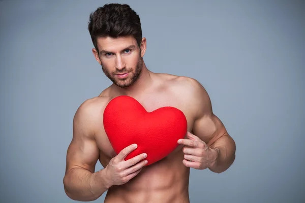 Muscular man holding heart shape — Stock Photo, Image